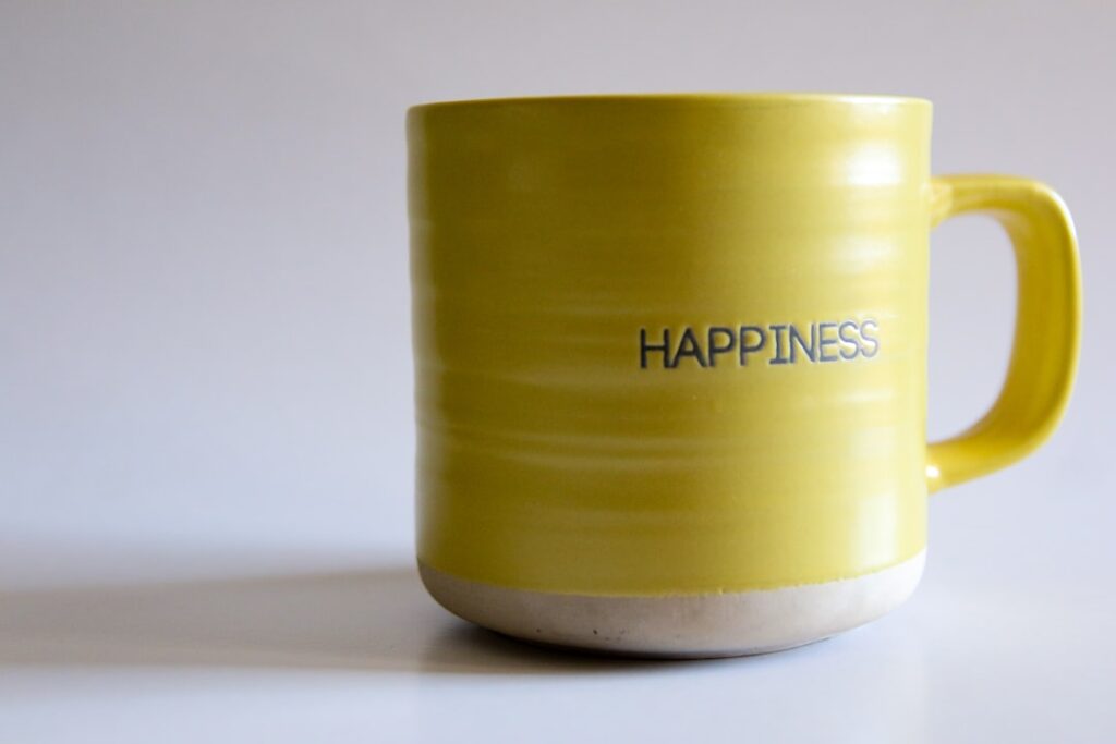 A yellow coffee mug with the words happiness written on it