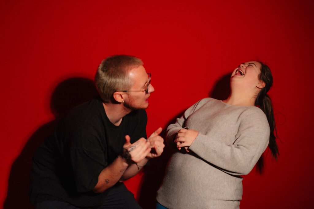 A man and woman laughing against a red background
