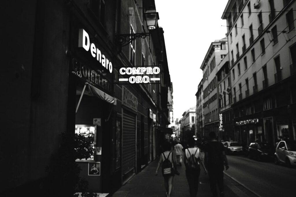 People walk down a street with shops and buildings.