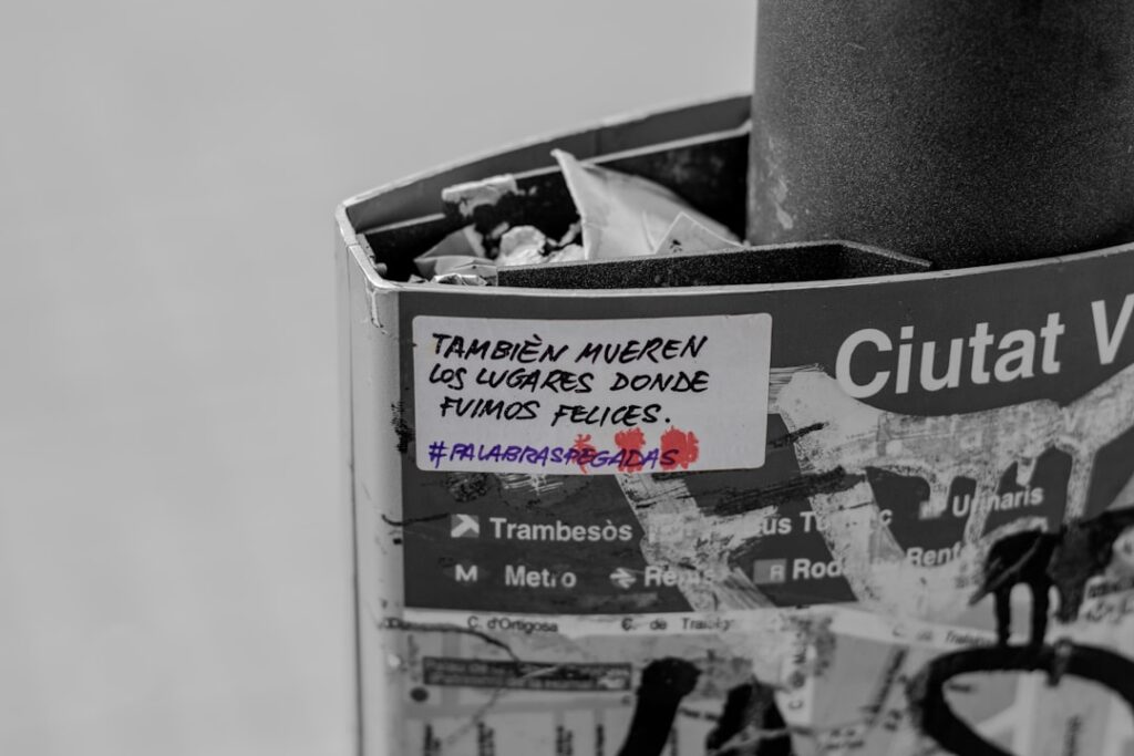 Street pole with spanish text sticker and red paint.